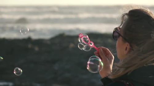 Woman Blowing Bubbles at the Beach on Sunny Day