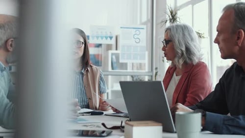 Female Business Leader Talking with Mixed-Aged Associates at Office Meeting