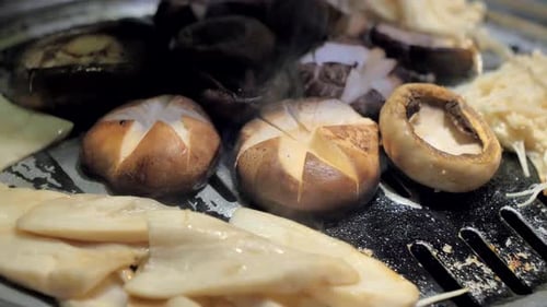 The Cook Prepares Mushrooms on Korean BBQ Gril Plate