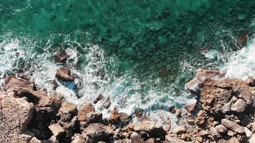 Ocean Waves Crashing Against Rocky Beach Creating White Foam and Splashing