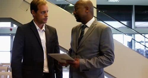 Businessmen Discussing Information on a Tablet Indoors