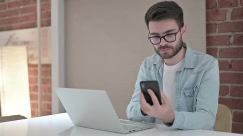 Young Adult Using Laptop and Mobile Phone Indoors