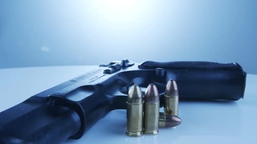 Gun Control. 9-mm-Handfeuerwaffe mit Kugeln, die sich auf einer reflektierenden Oberfläche drehen