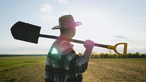 Farmer with Shovel in Field at Daytime