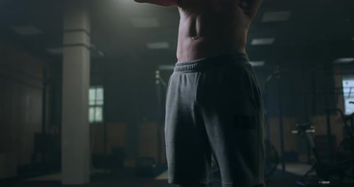 A Strong Man Holding Dumbbells in His Hands Performs Bends in the Gym, Sweating From a Hard Workout