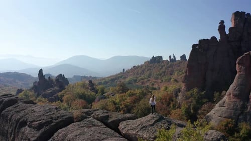 Aerial video with a woman at the edge of stunning rock formation