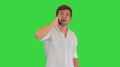 Happy Young Man Talking on Mobile Phone and Smiling on a Green Screen, Chroma Key.