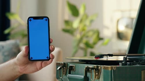 Hand Holds Smartphone with Chroma Key and Record Player