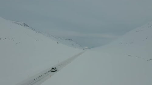 4K-Drohnenaufnahmen von Autofahren in verschneiter Landschaft.