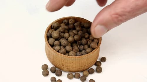 Close Up of Hand Grabbing Peppercorns from Bowl