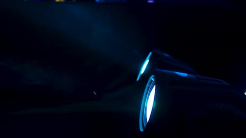 Nahaufnahme von professionellen Scheinwerfern, die schnell die Farben wechseln. Rauch macht Lichtstrahlen sichtbar.