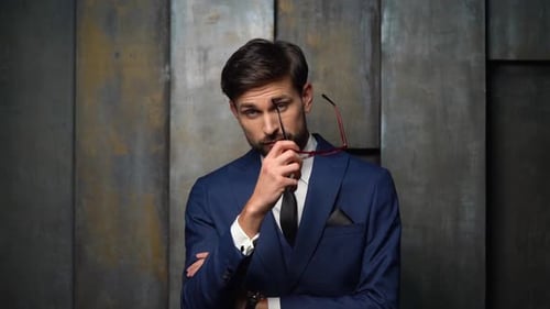 Thoughtful Man in Blue Suit Removes Glasses