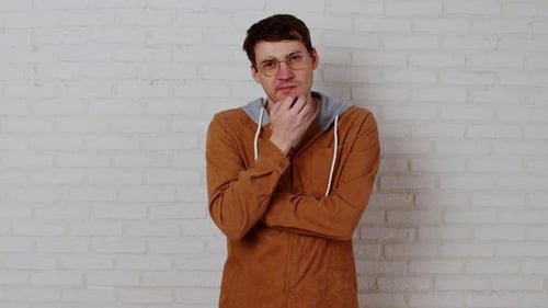 Thoughtful Man Posing Indoors Against a White Wall