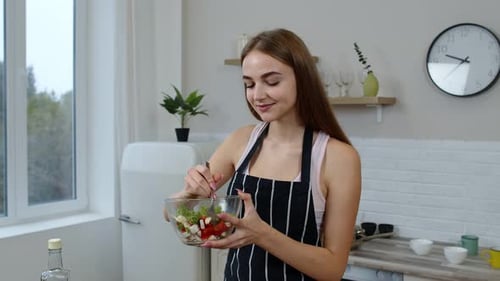 Woman Mixing Salad in Kitchen and Eating