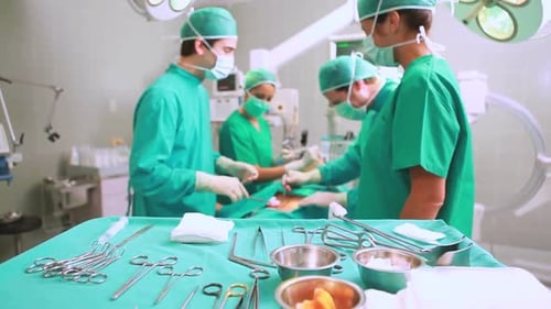 Chirurgische Instrumente werden auf einem OP-Tray angezeigt, während Chirurgen operieren