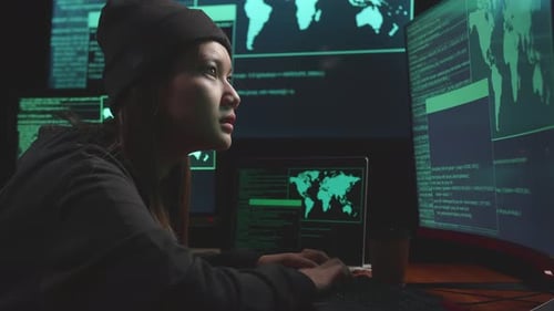 Young Asian Woman Hacker Using Computer Hacking, Code On Multiple Computer Screens