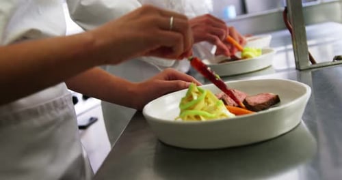 Close-up of team of chefs garnishing dishes