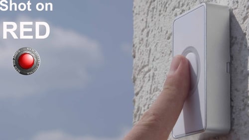 Finger presses modern white doorbell on textured wall