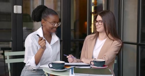 Multiethnische Mädchen arbeiten im Café mit Papieren