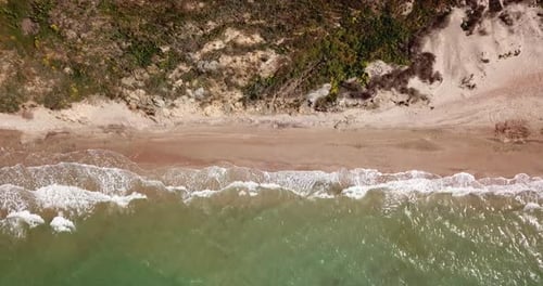 Vue de haut en bas des vagues se brisant dans le sable, survolant une plage de sable tropicale et des vagues