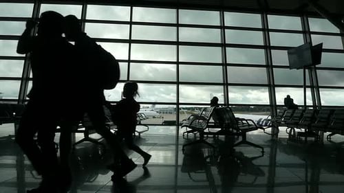 Travelers Walking Along Window in Airport Terminal, People Silhouettes Walking.