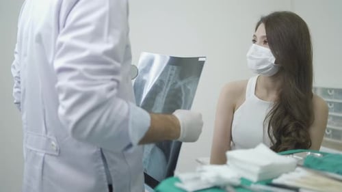 Doctor holding x-ray film and giving for medical cosmetic plastic surgery to woman at hospital