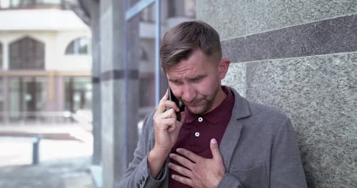 Un homme d'affaires parle au téléphone et suffoque en toussant près d'un centre de bureaux