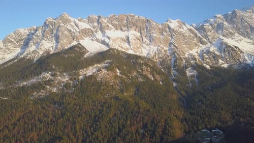 Aerial view flying up Zugspitze scenic snowy landmark alpine mountain peak under blue sky