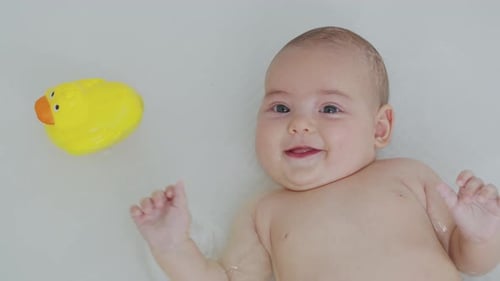 Happy Infant Plays in Bath with Rubber Duck