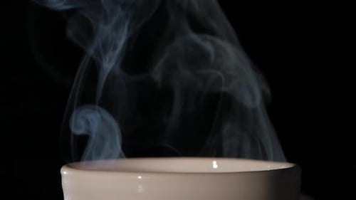 Steam rising from a cup on a black background