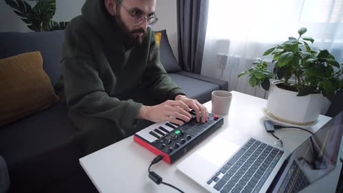 Man Plays MIDI Keyboard at Home on Couch