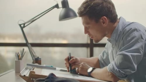 Engineer Draws Buildings on the Table Using a Pencil and Ruler
