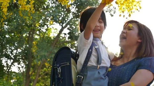 Asian Mother Holding Her Son While Walking In The Park Back To School Concept Slow Motion