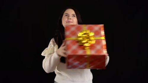 Woman Holds Christmas Gift on Black Background