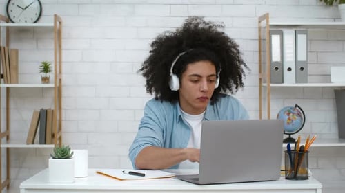 Young adult works on laptop in home office