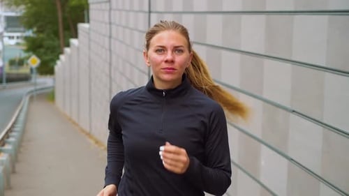 Athletic woman jogging in empty city near road