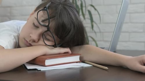 Tired Child Sleeping with Book and Glasses