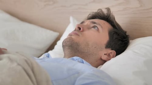 Homme mal à l'aise se réveillant de son sommeil au lit