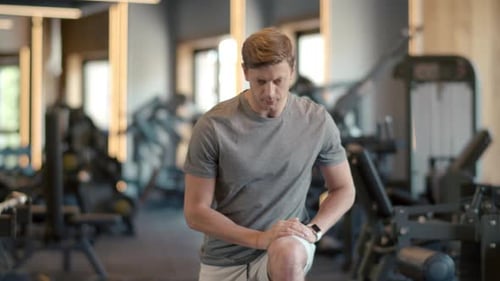 Attractive Fitness Man Warming Up Legs at Gym. Sportsman Making Squats at Gym.