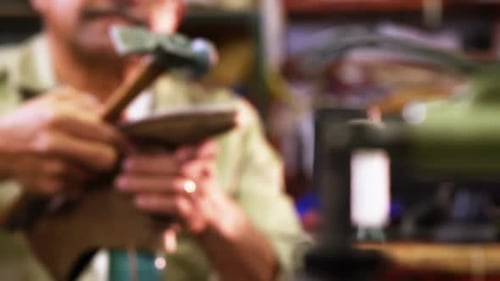 Adult Repairing Shoe with Hammer in Workplace