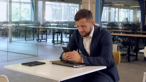Young Man Using Phone at Office Table