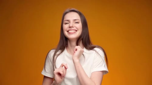 Woman Dancing Happily in Front of Orange Background