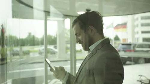 Man in Suit Smiling While Using Phone