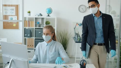 Arab Man in Mask and Gloves Leaving Office Doing High-five with Caucasian Woman Colleague