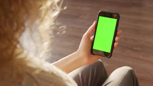 Close Up of an Unrecognisable Blond Curly Businesswoman Holding a Smart Phone with a Green Screen