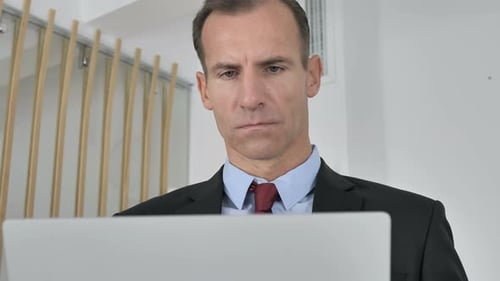 Middle Aged Businessman Working On Laptop in Office
