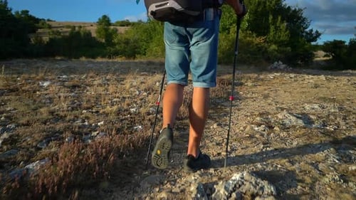 Back View of Male Hiker is Walking Along Rocky Area and Smiling on Summer Day Spbd