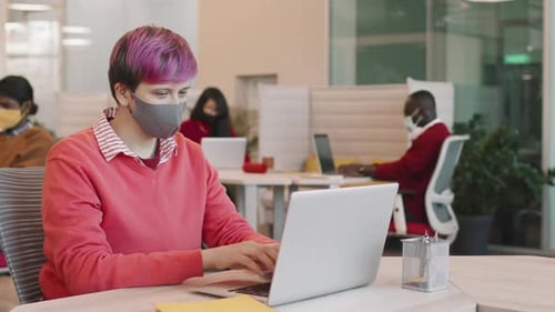 Femme hipster portant un masque facial travaillant au bureau