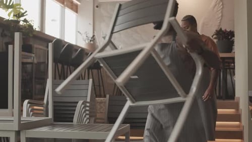 Diverse Waiters Arranging Chairs in Restaurant