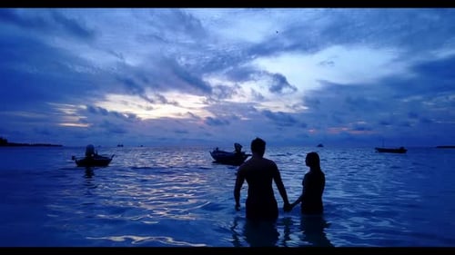 Two lovers posing on tranquil coastline beach vacation by aqua blue ocean and white sand background